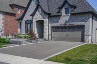 this is an open, large house with grey brick sidings and windows and a white garage