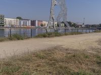 large metal sculptures of people facing each other on dirt path next to building complex with large metal structures in background