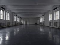 large open building with long floor space in middle of room with white walls and windows