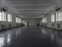 large open building with long floor space in middle of room with white walls and windows