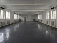 large open building with long floor space in middle of room with white walls and windows