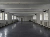 large open building with long floor space in middle of room with white walls and windows