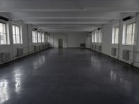 large open building with long floor space in middle of room with white walls and windows