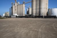 large steel silos in an open field on a sunny day with no people in sight