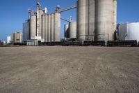 large steel silos in an open field on a sunny day with no people in sight