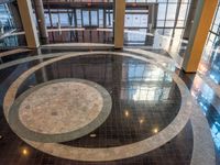 a lobby in an office building, with a circular marble floor and black tile floors