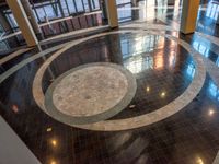 a lobby in an office building, with a circular marble floor and black tile floors