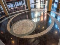 a lobby in an office building, with a circular marble floor and black tile floors