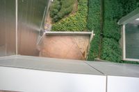 an outdoor area with various green plants and plants growing on the walls, looking down