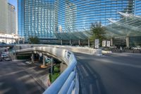 an empty street under a large bridge with glass buildings in the background with bicycle racks