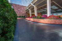 the walkway leading to a hotel or other building is paved with cement and plants at the side