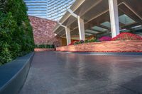 the walkway leading to a hotel or other building is paved with cement and plants at the side