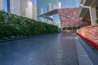 a walkway next to some tall buildings and red flowers in the foreground of it