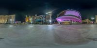 a skateboarder riding at night on the road in front of a casino and hotel