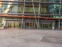 the people walking past a building have large windows at it's sides and doors