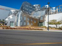 silver building with a curved design near an intersection and a city street scene behind it