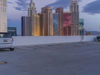 a white minivan parked in a parking lot outside a city building with an roller coaster