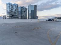 a car park area with cars parked in the lot, and some high rise buildings