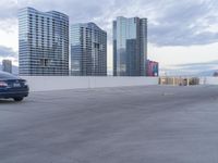 a car park area with cars parked in the lot, and some high rise buildings