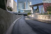 some glass and metal building a long highway and buildings a bench and a road with trees on it