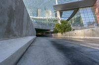 some glass and metal building a long highway and buildings a bench and a road with trees on it