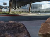 a woman taking pictures near a giant rock on the side of the street with a phone