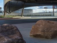 a woman taking pictures near a giant rock on the side of the street with a phone