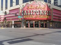 a car is driving down the street in front of a casino building with the word california hotel on it