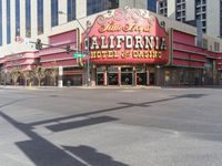 a car is driving down the street in front of a casino building with the word california hotel on it