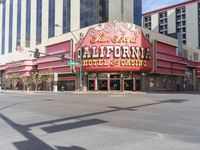 a car is driving down the street in front of a casino building with the word california hotel on it