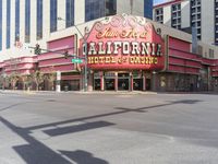 a car is driving down the street in front of a casino building with the word california hotel on it