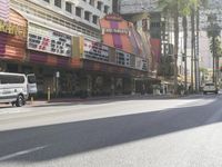 a white van is parked on the side of the road in front of a movie theater