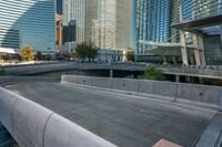 concrete walkway alongside road near skyscraper buildings in city setting and reflection on glass windowed wall