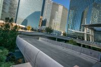 concrete walkway alongside road near skyscraper buildings in city setting and reflection on glass windowed wall