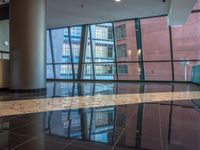 a large lobby of a building with high rise windows with a flooring in front of a reflection