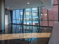 a large lobby of a building with high rise windows with a flooring in front of a reflection