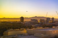 a photo of some buildings and trees and mountains in the distance as the sun sets