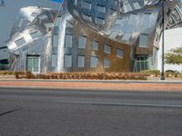 an abstract building with large silver sculptures and trees along the side of the street in front of it