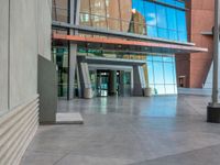 an empty plaza with stairs and windows on both sides and a sky reflection in the center