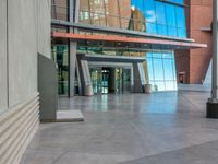 an empty plaza with stairs and windows on both sides and a sky reflection in the center