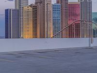 there are several skyscrapers behind a parking lot with a person on a skateboard