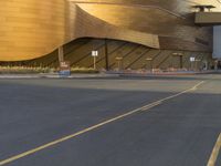 a street view of a curved metallic building in a city with traffic passing by it