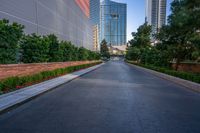 a view looking down the road from a sidewalk leading up to skyscrapers, on a clear day