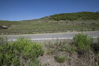 a view of a highway with mountains and buildings in the distance, in the spring