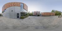 360 - lens image of two people walking past the library building and some buildings in background