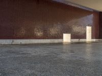 a woman walks through a hallway near a building and a wall with brickwork on it