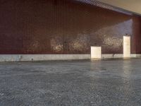 a woman walks through a hallway near a building and a wall with brickwork on it