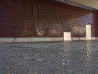 a woman walks through a hallway near a building and a wall with brickwork on it