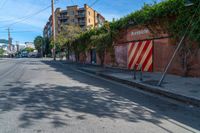 a empty street next to several tall brick buildings with green vines on it's side