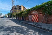 a empty street next to several tall brick buildings with green vines on it's side